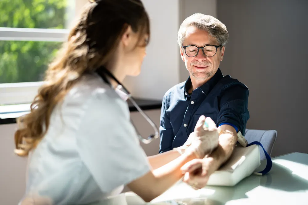A patient seated comfortably while a clinician prepares for a blood draw
